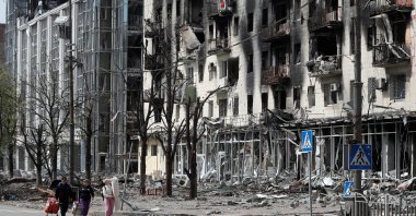People walk along a street near a building damaged during the Ukraine-Russia conflict in the southern port city of Mariupol, Ukraine, April 25, 2022. (Reuters Photo)