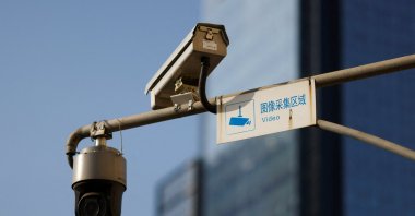 A video surveillance sign is seen next to Hikvision surveillance cameras overlooking a street in Beijing, China, Dec.14, 2021. (Reuters Photo)