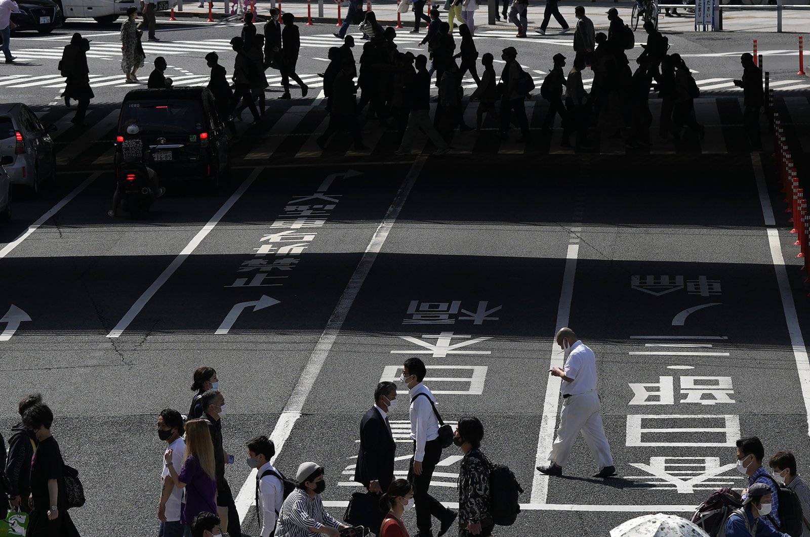 People wearing face masks walk across a pedestrian crossing in Tokyo, Japan, April 22, 2022. (AP Photo)