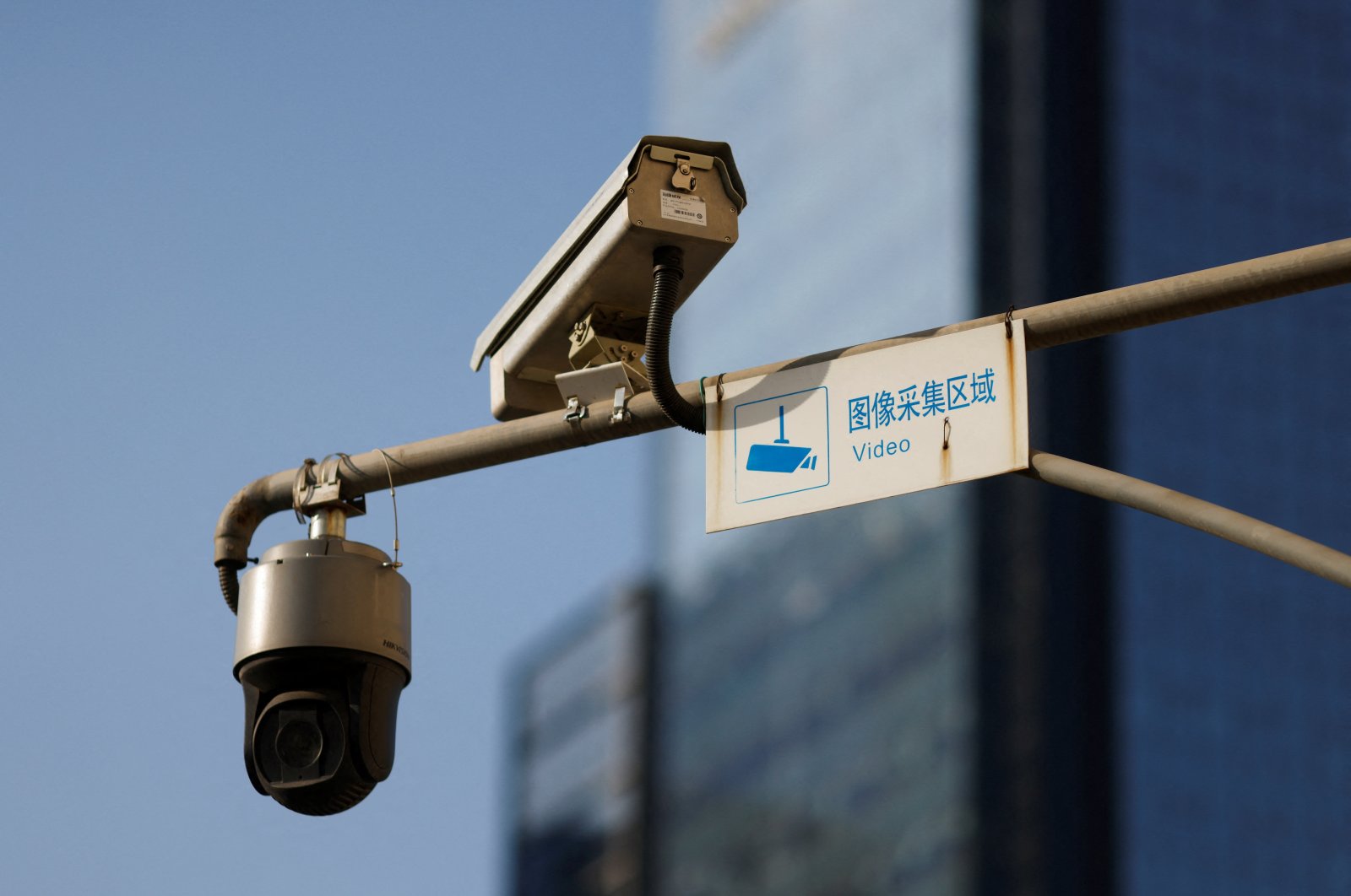 A video surveillance sign is seen next to Hikvision surveillance cameras overlooking a street in Beijing, China, Dec.14, 2021. (Reuters Photo)