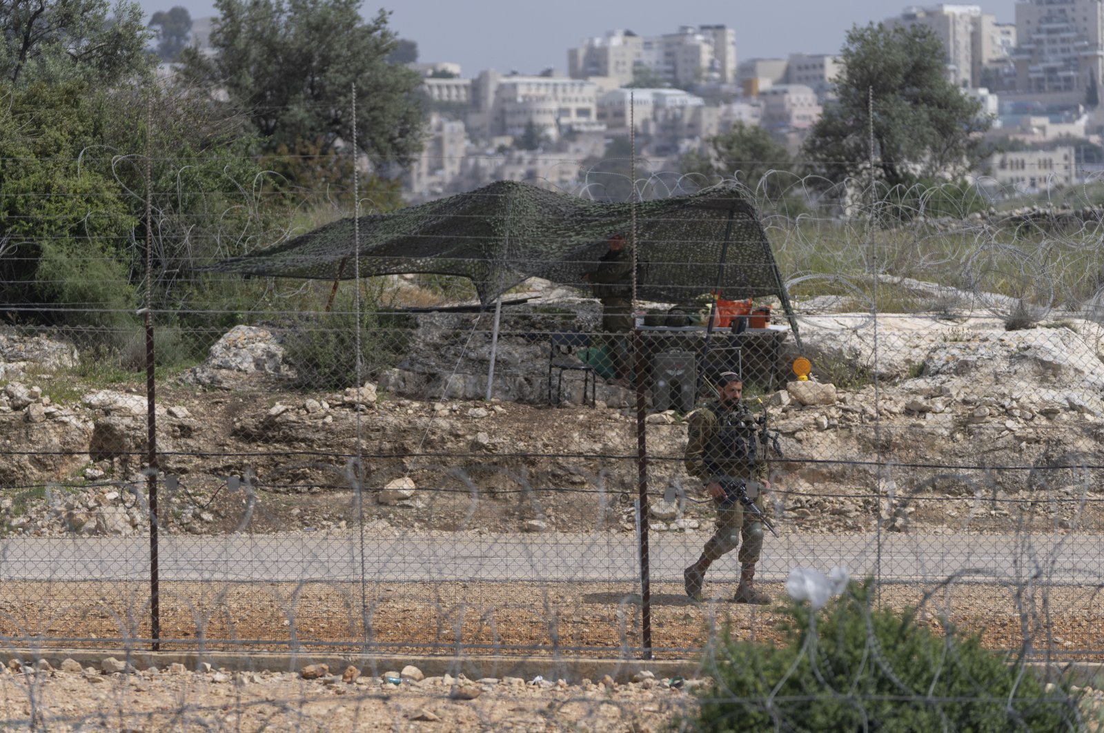 An Israeli soldier guards an opening in Israel&#039;s West Bank separation barrier that was reinforced with barbed wire to prevent Palestinians from crossing into Israel, in Nilin, west of Ramallah, April 10, 2022. (AP Photo)