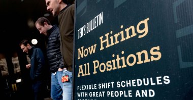 Pedestrians walk past a “Now Hiring” sign in Arlington, Virginia, U.S., March 16, 2022. (AFP Photo)