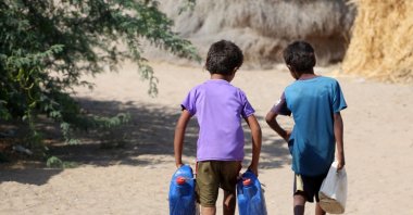Yemeni children carry jerrycans at a makeshift camp for people who fled fighting between Huthi rebels and the Saudi-backed government forces in the village of Hays near the conflict zone in Yemen&#039;s western province of Hodeida, Jan. 28, 2022. (AFP Photo)