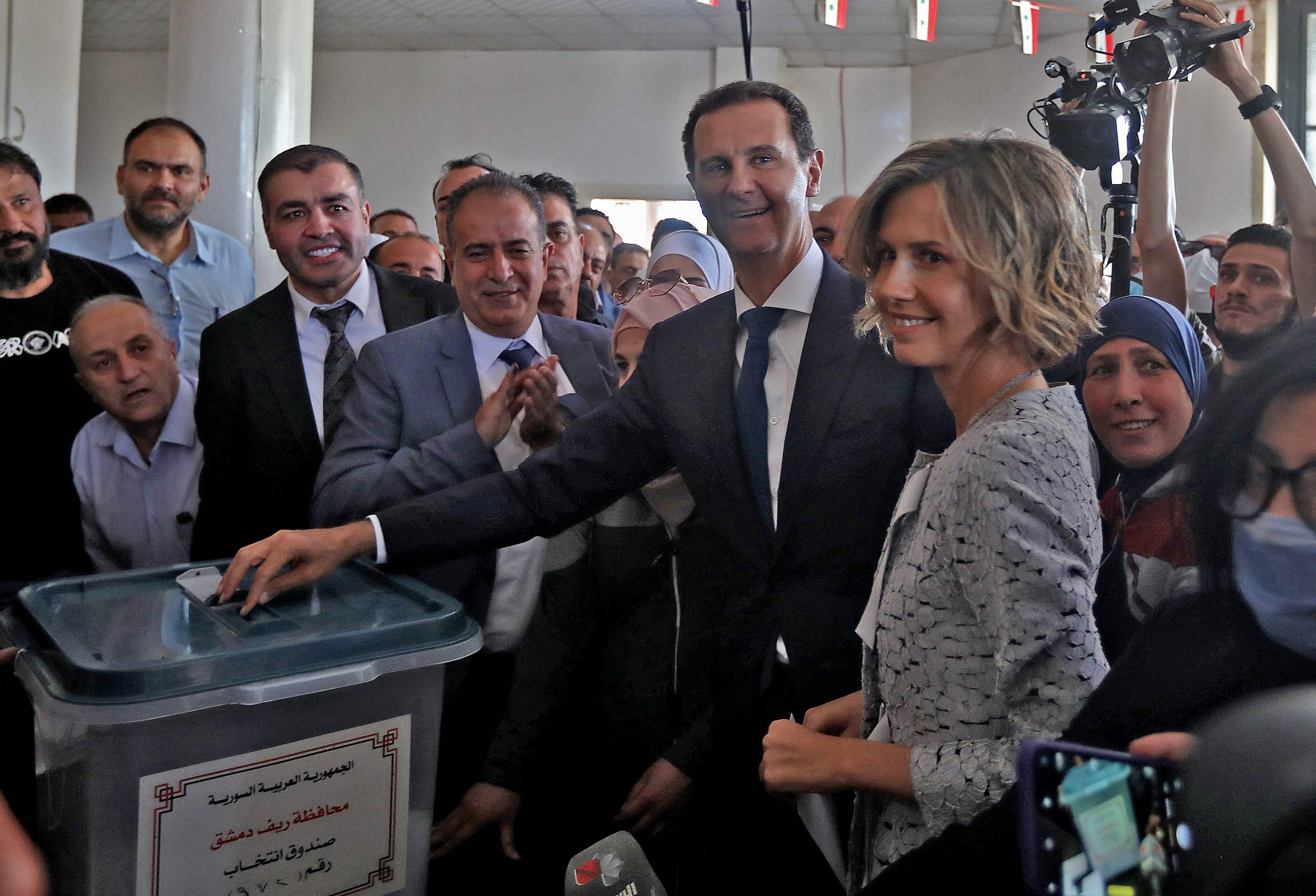 In this file photo taken on May 26, 2021, Syrian President Bashar al-Assad (C) and his wife Asma (R) cast their votes at a polling station in Douma, near Damascus, May 26, 2021. (Photo via AFP)