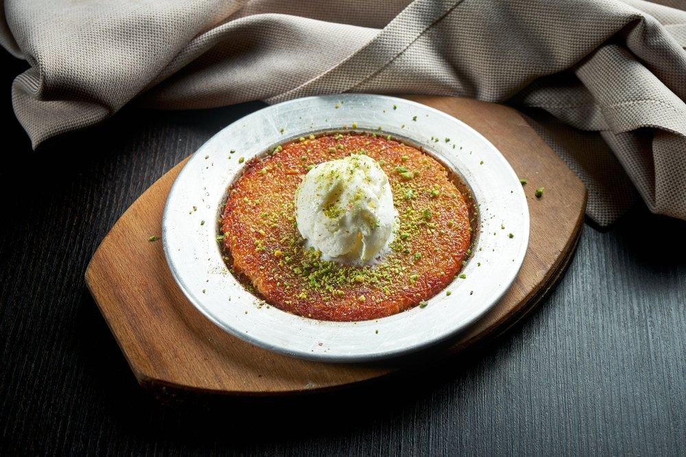 The appetizing Turkish sweet 'künefe' is made with shredded filo pastry, honey and pistachios, and topped with ice cream. (Shutterstock Photo)