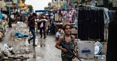 A Syrian youth carries a toy rifle in a market street in the northern city of Raqa, April 28, 2022. (AFP Photo)