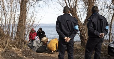 Frontex border officers stand by migrants on the shore near the village of Skala Sikamineas on the island of Lesbos, Greece, March 1, 2020. (Getty Images)