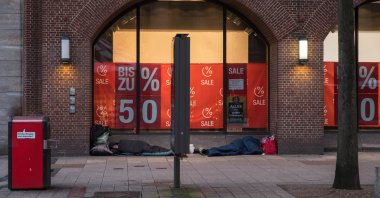 Homeless people sleep early in the morning on the street next to expensive shops in a sleeping bag, Hamburg, Germany, January 2018. (Shutter Stock Photo)