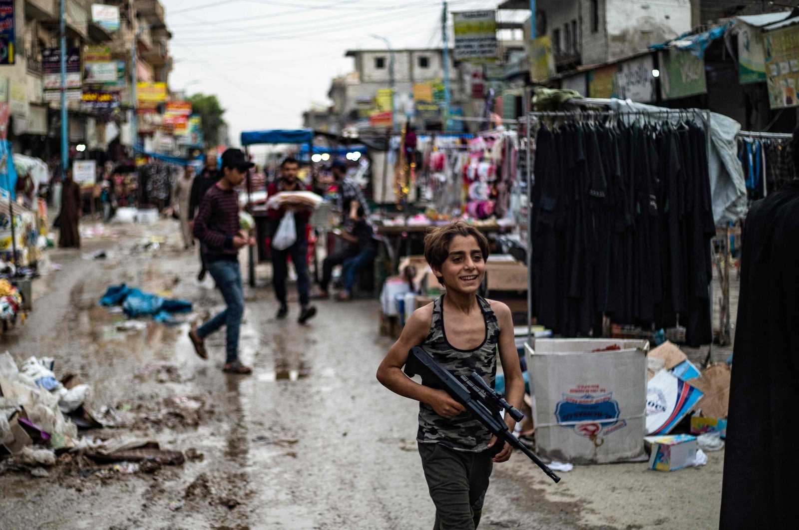 A Syrian youth carries a toy rifle in a market street in the northern city of Raqa, April 28, 2022. (AFP Photo)