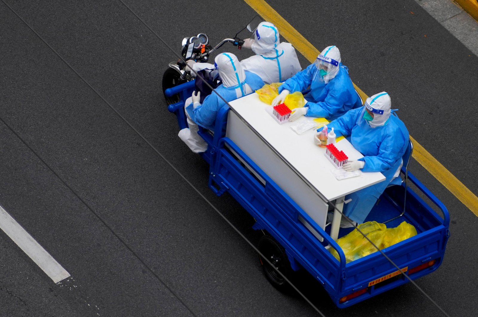 Workers in protective suits ride an electric tricycle on a street during lockdown amid COVID-19 pandemic, Shanghai, China, April 29, 2022. (Reuters Photo)
