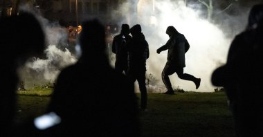 People are silhouetted by smoke after protests broke out at Rosengard in Malmo, Sweden, April 17, 2022. (AP Photo)