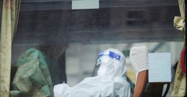A woman in a protective suit sits inside a bus on a street during lockdown, amid the COVID-19 pandemic, in Shanghai, China, May 1, 2022. (Reuters Photo)