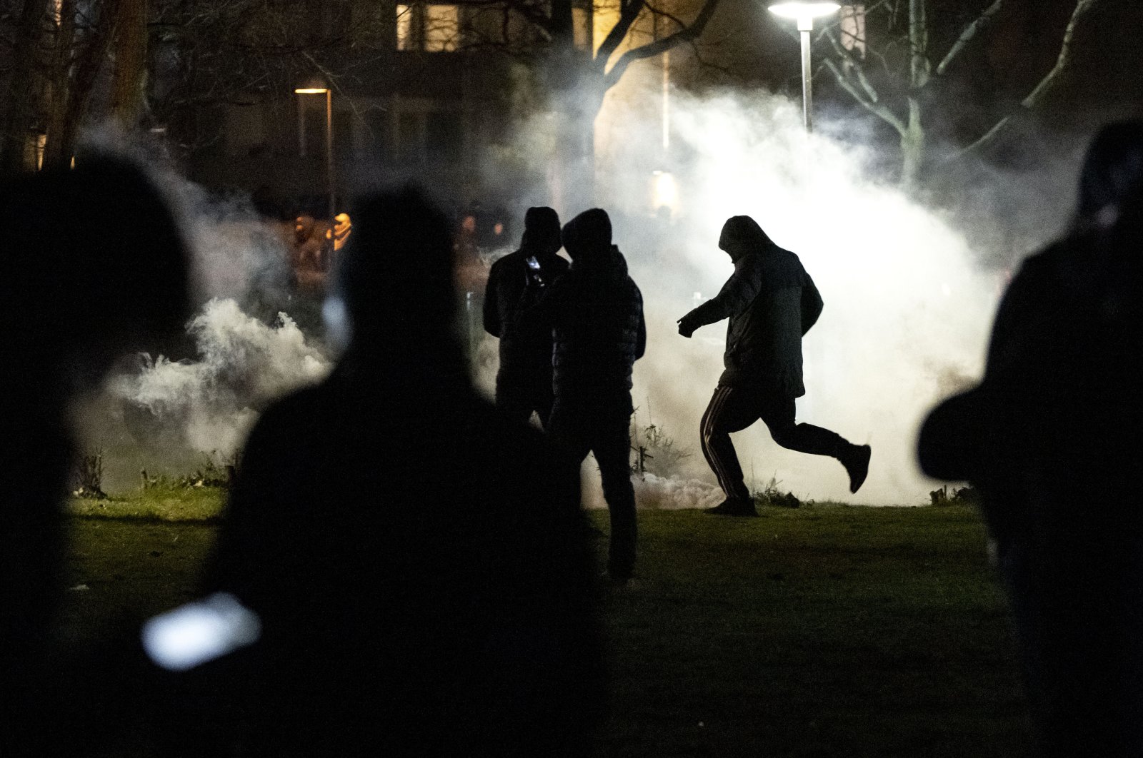 People are silhouetted by smoke after protests broke out at Rosengard in Malmo, Sweden, April 17, 2022. (AP Photo)