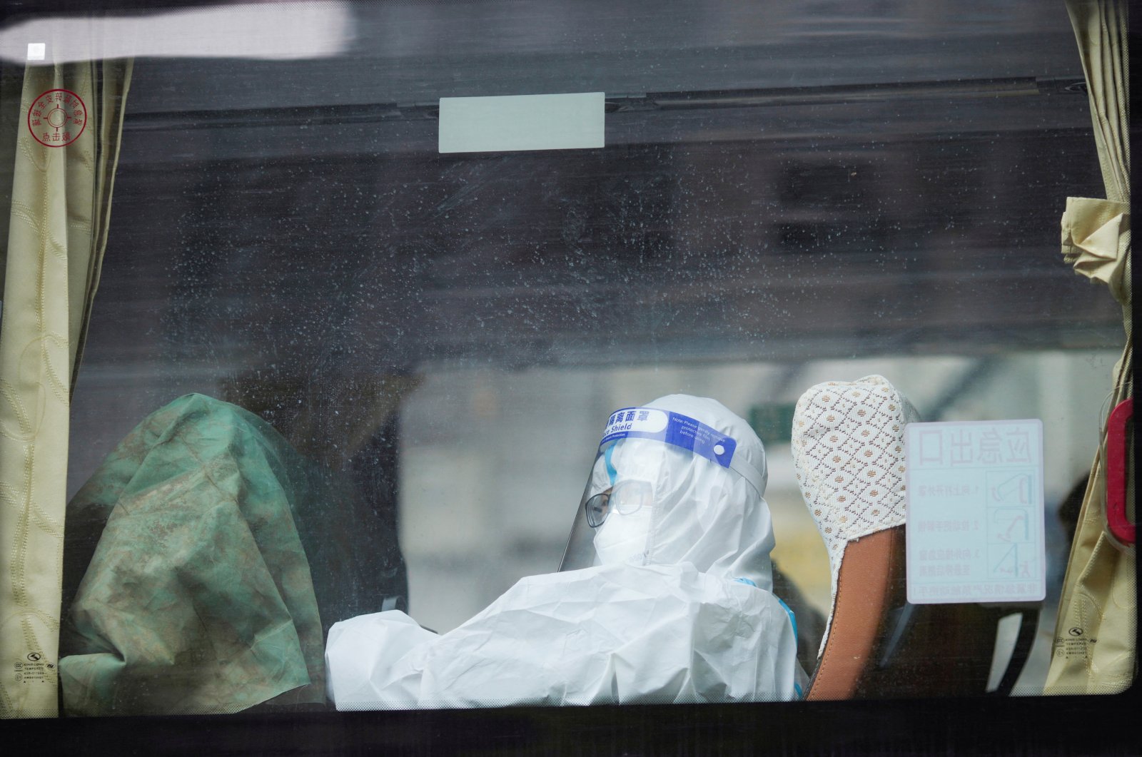 A woman in a protective suit sits inside a bus on a street during lockdown, amid the COVID-19 pandemic, in Shanghai, China, May 1, 2022. (Reuters Photo)