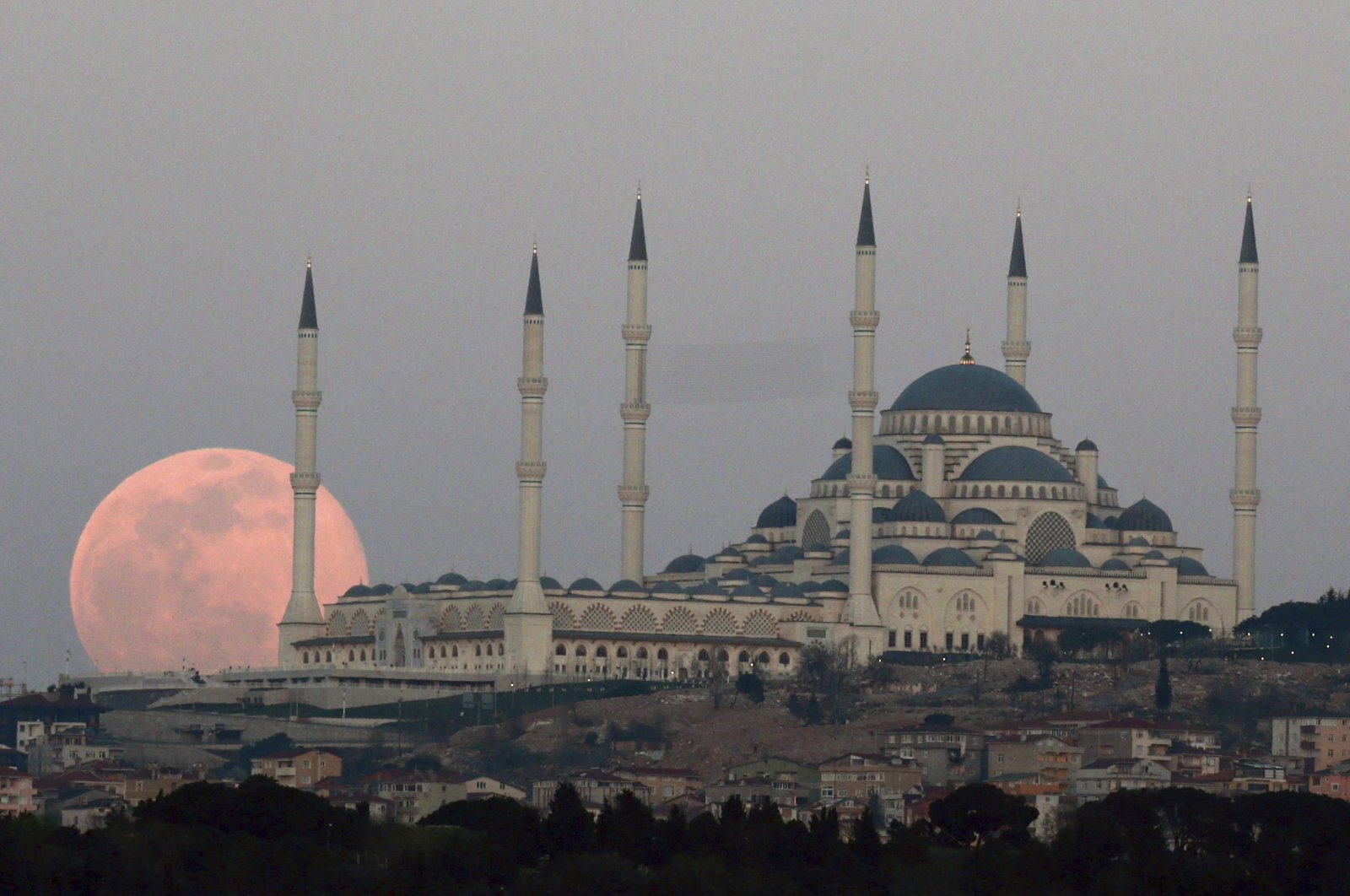 The full moon rises Sunday, March 28, 2021 over the sky in Istanbul, with the Çamlıca Grand Mosque, the largest mosque in Asia Minor. The March full moon is called the &quot;Worm Moon&quot;. (AP File Photo)