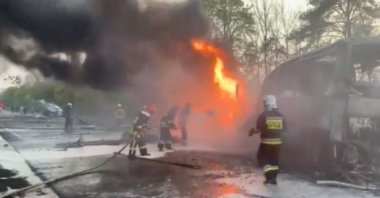 Firefighters spray water on a vehicle on fire after a fuel truck collided with a bus on the Kyiv-Chop highway, in the Rivne region of Ukraine, in this still image taken from a handout video released on May 3, 2022. (Reuters Photo)
