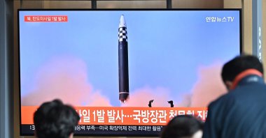 People watch a television screen showing a news broadcast with file footage of a North Korean missile test at a railway station in Seoul, South Korea, May 4, 2022. (AFP Photo)
