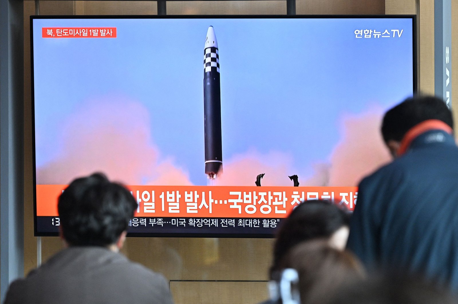 People watch a television screen showing a news broadcast with file footage of a North Korean missile test at a railway station in Seoul, South Korea, May 4, 2022. (AFP Photo)