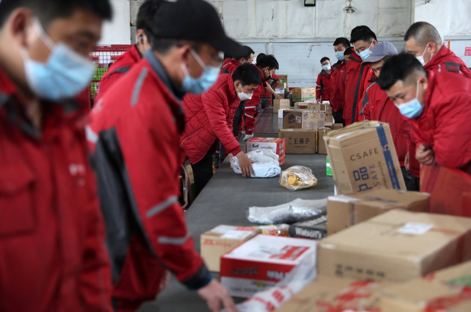 Employees wearing masks check goods on a conveyor belt at JD.com&#039;s smart logistics center in Beijing, China, April 28, 2022. (Reuters Photo)