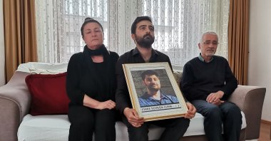 Emre Soykök's mother, brother and father pose with a photo of the young man in their home, in the capital Ankara, Turkey, May 5, 2022. (DHA PHOTO) 
