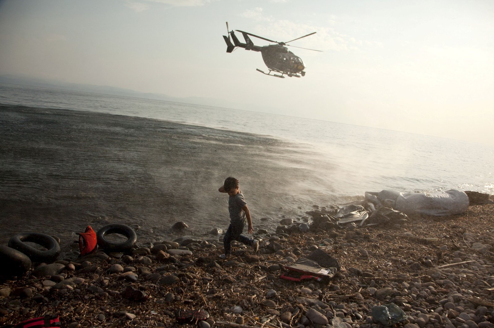 A Frontex helicopter patrols over a Syrian child that has just arrived at a beach on the Aegean island of Lesbos, Greece, Aug. 10, 2015. (Reuters Photo)