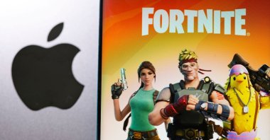 Fortnite game graphic is displayed on a smartphone in front of the Apple logo, May 2, 2021. (Reuters Photo)