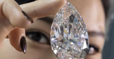A Christie's employee holds "The Rock," a white diamond of 228,31 carats that is the largest white diamond ever seen throughout auction market history, during a preview at Christie's, Geneva, Switzerland, May 6, 2022. (EPA Photo)