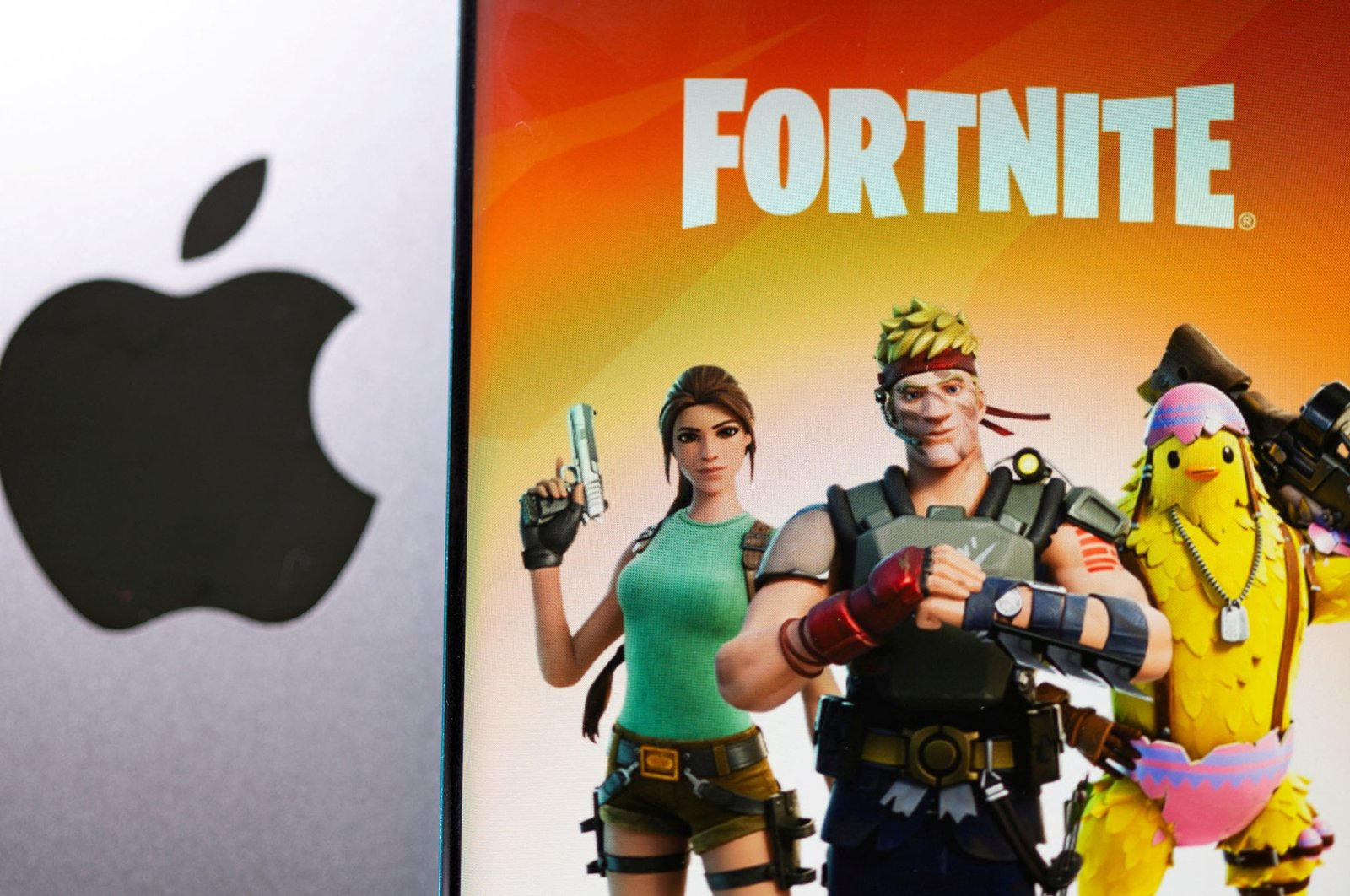 Fortnite game graphic is displayed on a smartphone in front of the Apple logo, May 2, 2021. (Reuters Photo)