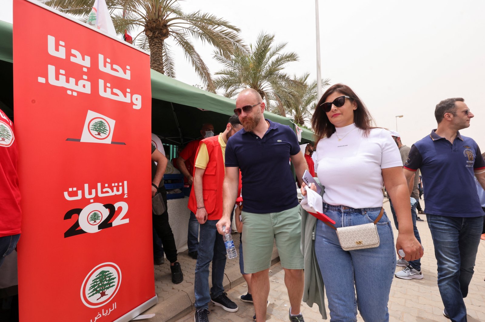 Lebanese expats walk in front of an election banner as they arrive to cast their vote in Lebanon&#039;s parliamentary election at the Lebanese Embassy in Riyadh, Saudi Arabia, May 6, 2022. (Reuters Photo)