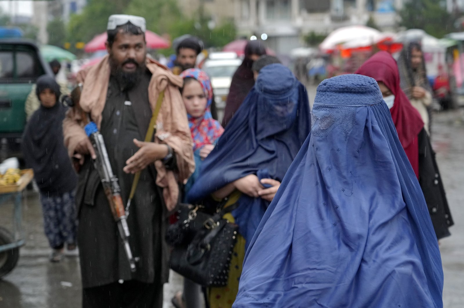 Women walk through the old market as a Taliban fighter stands guard, in the city of Kabul, Afghanistan, May 3, 2022. (AP Photo)