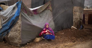 A young Syrian woman holds a baby in a refugee camp for displaced people supported by the Turkish Red Crescent in Sarmada district, north of Idlib city, Syria, Nov. 25, 2021. (AP Photo)