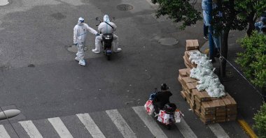 A policeman checks a delivery worker on scooter on the street during a Covid-19 coronavirus lockdown in the Jing'an district in Shanghai, China, May 7, 2022. (AFP Photo)