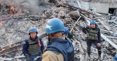 Emergency crew members stand around near burning debris after a school building was hit as a result of shelling, in the village of Bilohorivka, Luhansk, Ukraine, May 7, 2022. (State Emergency Services Handout via Reuters)