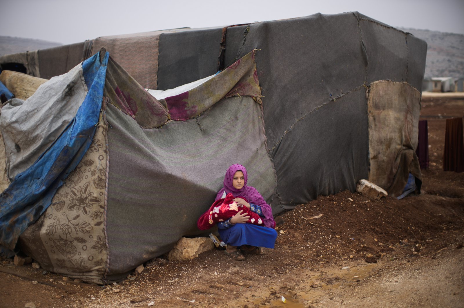 A young Syrian woman holds a baby in a refugee camp for displaced people supported by the Turkish Red Crescent in Sarmada district, north of Idlib city, Syria, Nov. 25, 2021. (AP Photo)