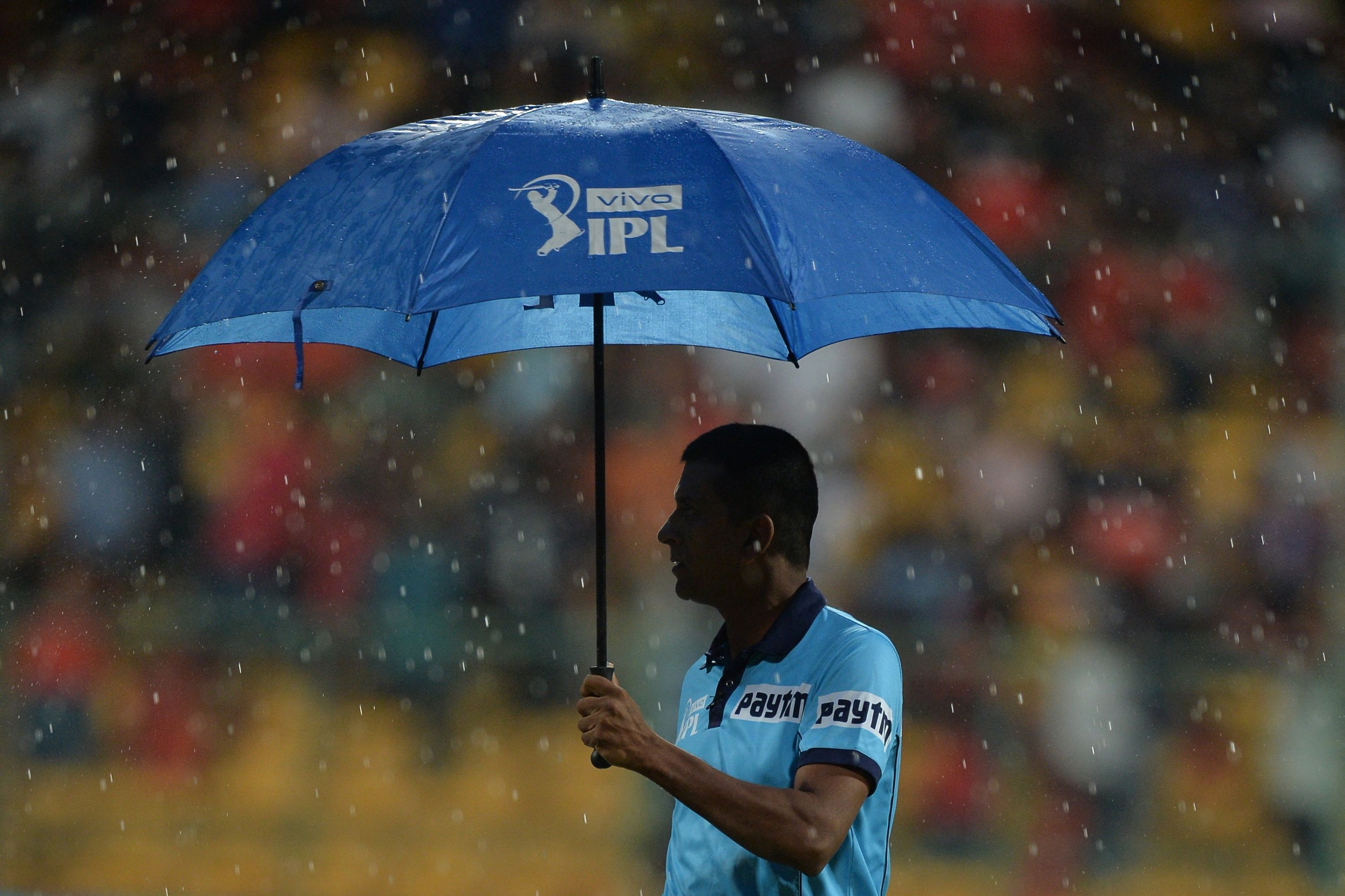 Seorang wasit berjalan ke tanah saat hujan menunda dimulainya pertandingan IPL, Bangalore, India, 30 April 2019. (AFP Photo)