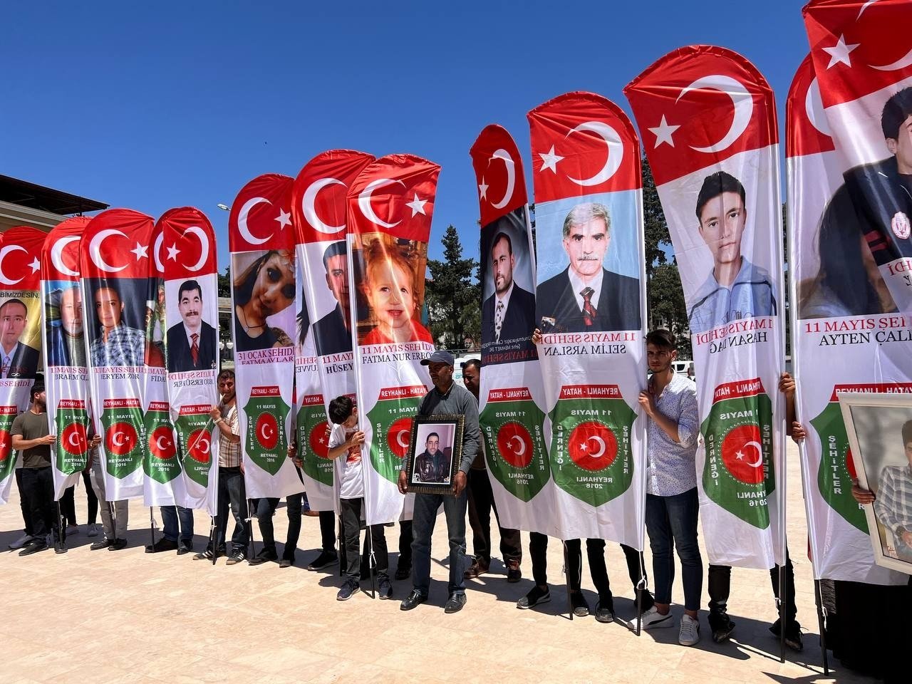 People hold pictures of victims during the remembrance events, in Reyhanlı, in Hatay, southern Turkey, May 11, 2022. (İHA PHOTO)
