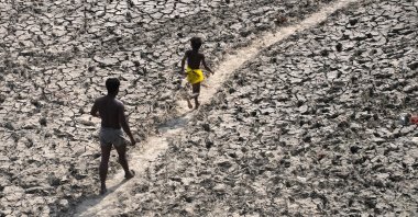 A man and a boy walk across the almost dried-up riverbed of the Yamuna following hot weather in New Delhi, India, May 2, 2022. (AP Photo)
