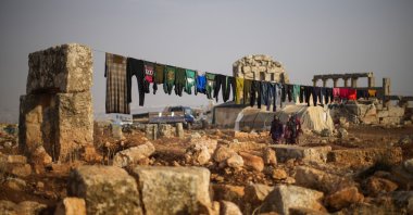 Displaced Syrian people walk next to ancient Roman-era ruins where they have set up their tents in the Sarmada district, north of Idlib city, Syria, Nov. 25, 2021. (AP Photo)