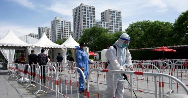 A worker disinfects the queue area of a swab test collection site for COVID-19 in Beijing, China, May 11, 2022. (AFP Photo)