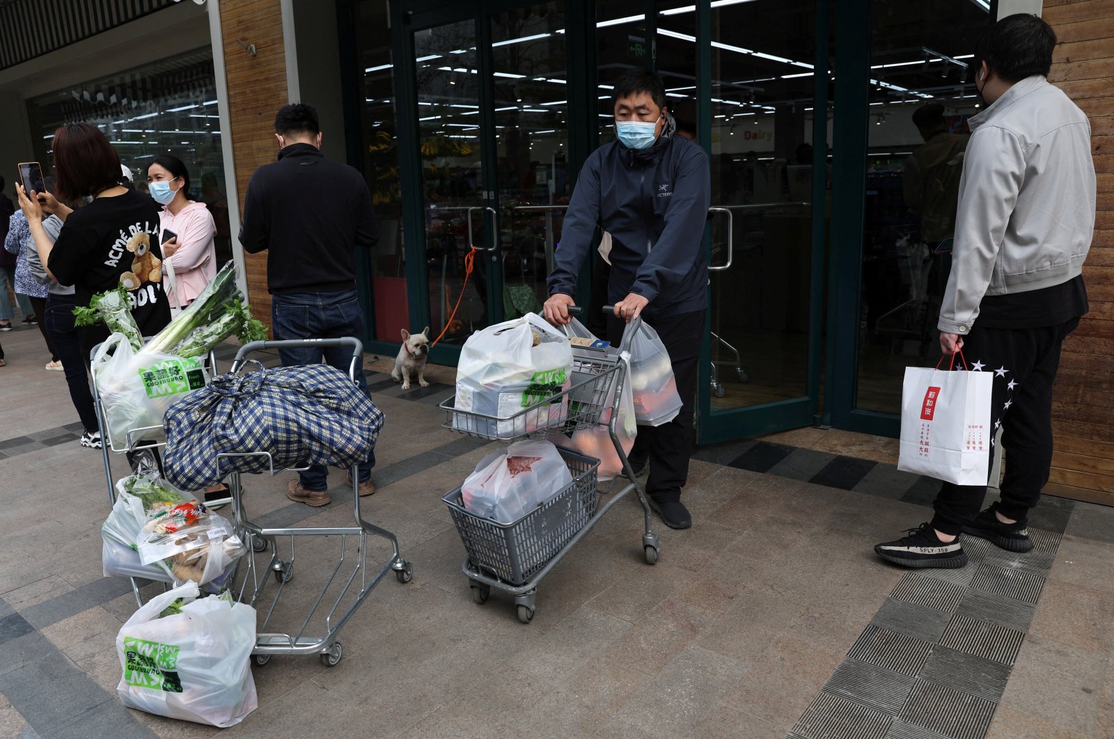 A customer pushes a cart carrying bags of goods as he leaves a supermarket in Beijing, China, April 25, 2022. (Reuters Photo)