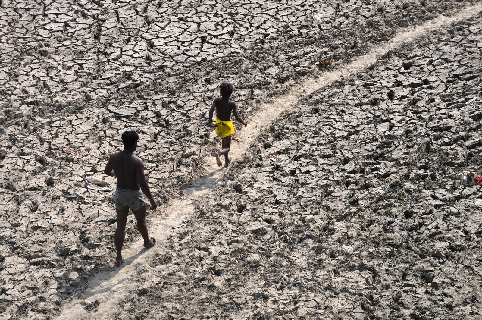 A man and a boy walk across the almost dried-up riverbed of the Yamuna following hot weather in New Delhi, India, May 2, 2022. (AP Photo)