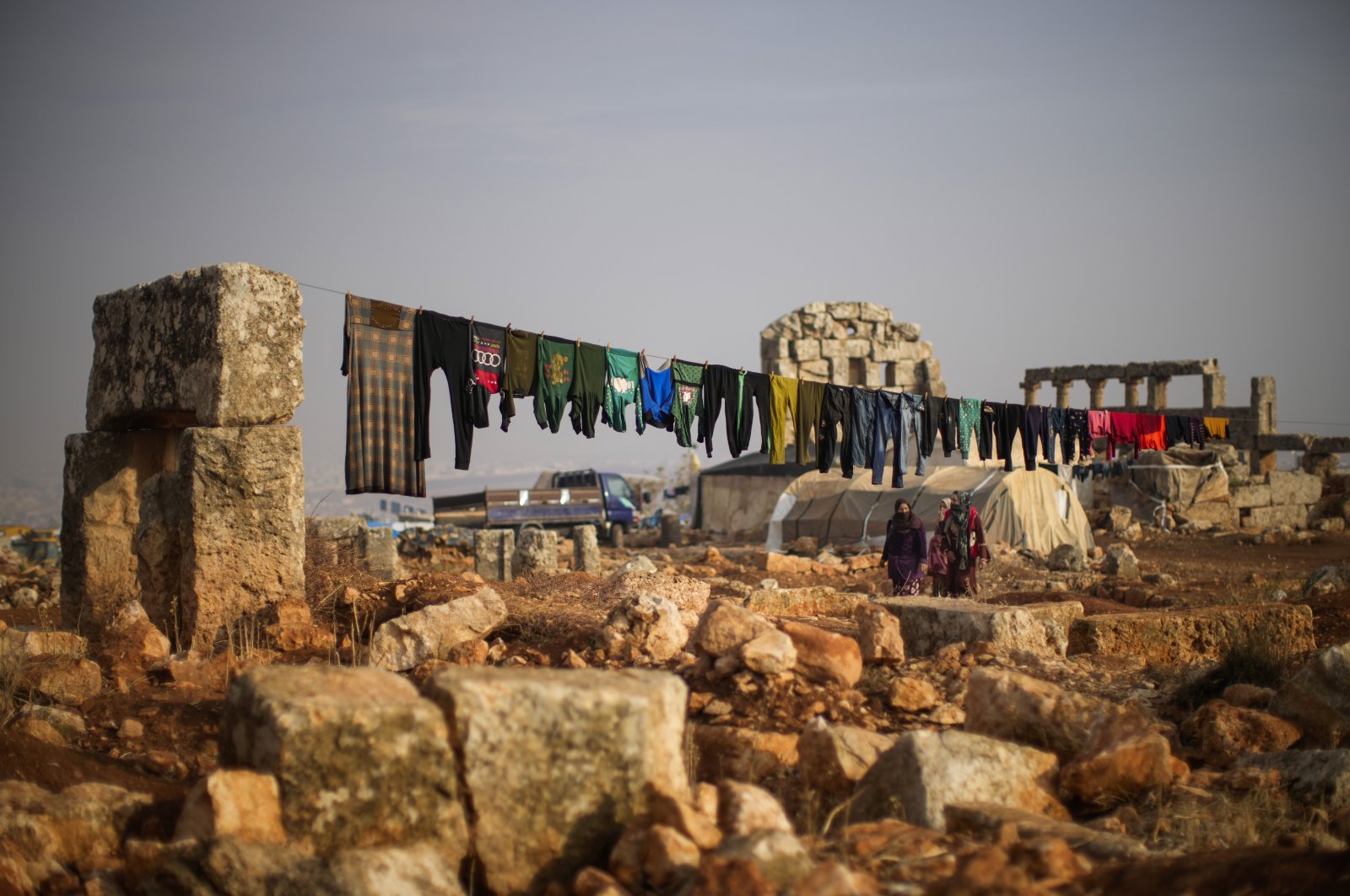 Displaced Syrian people walk next to ancient Roman-era ruins where they have set up their tents in the Sarmada district, north of Idlib city, Syria, Nov. 25, 2021. (AP Photo)
