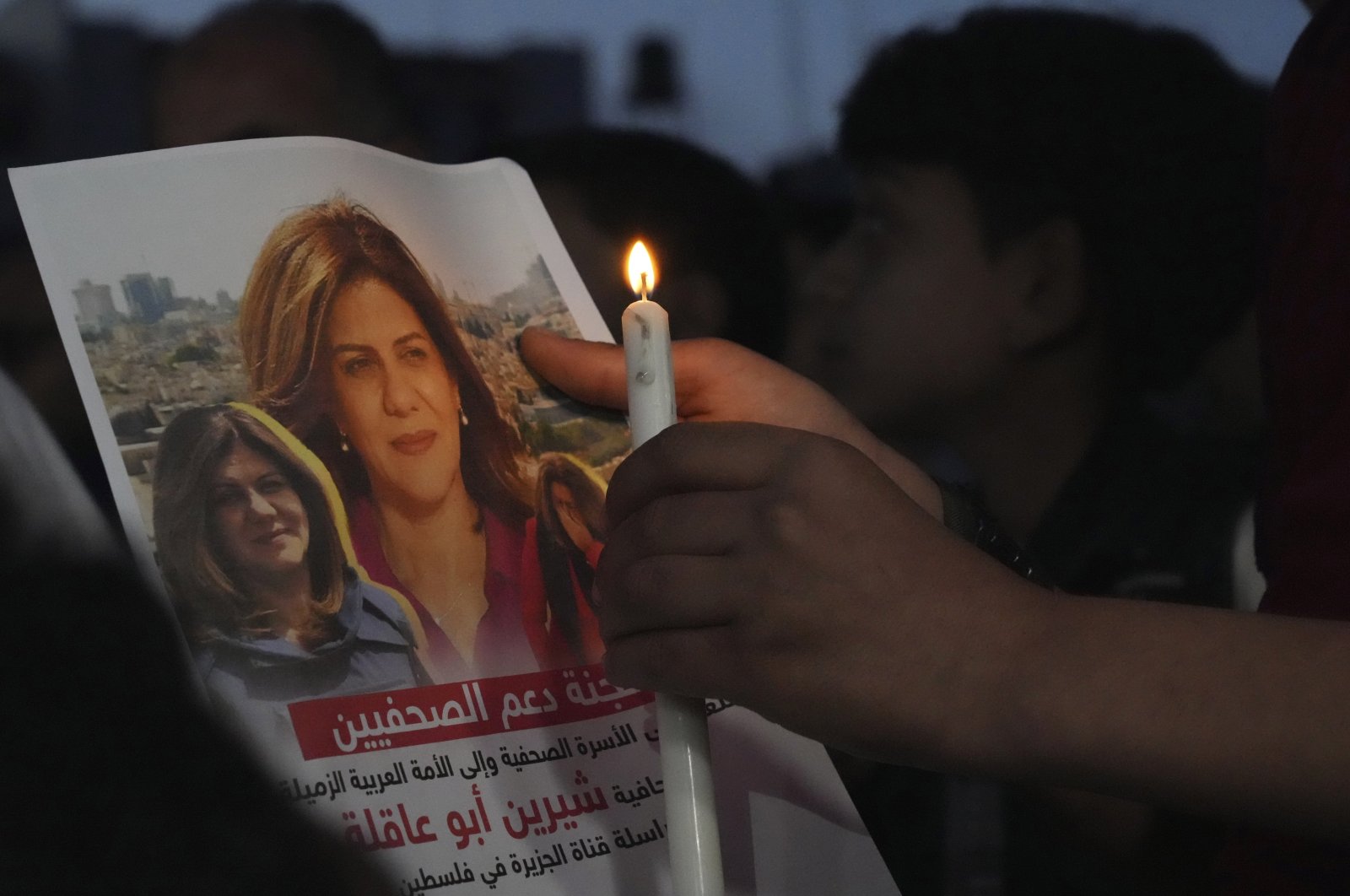 A Palestinian holds a candle and a picture of slain Al-Jazeera journalist Shireen Abu Akleh during a vigil in protest of her death, in front of the office of the Al-Jazeera network, in the Gaza Strip, Palestine, May 11, 2022. (AP Photo)