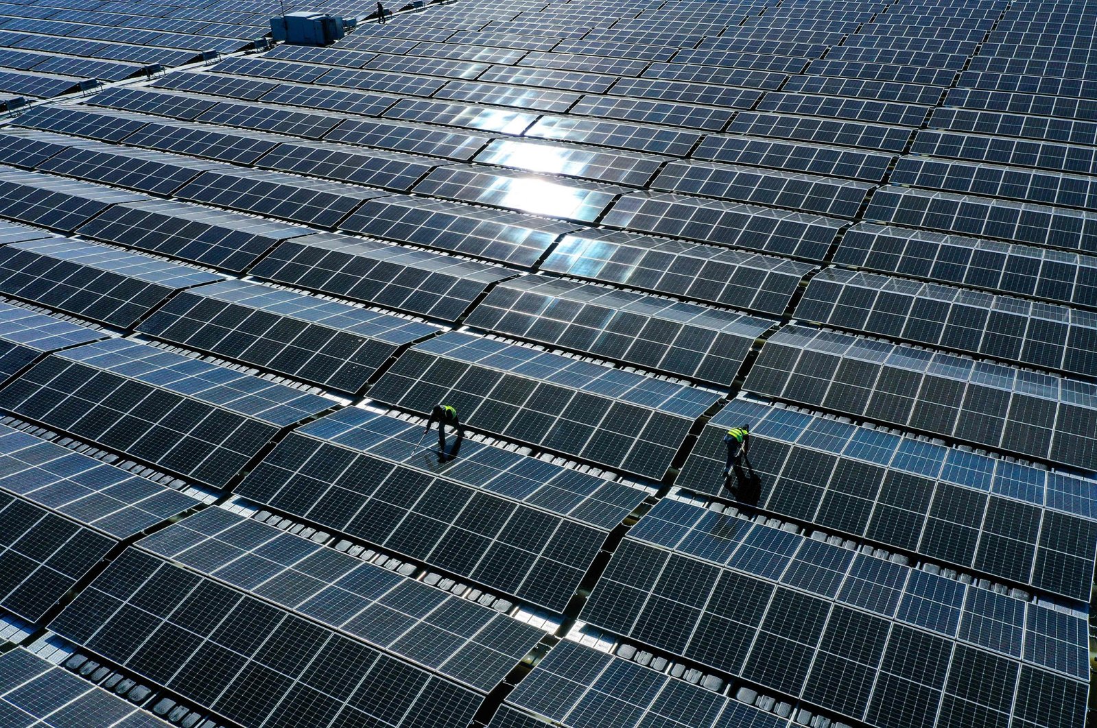 An aerial view shows workers assembling solar panels at a floating photovoltaic plant on the Silbersee lake in Haltern, western Germany, April 22, 2022. (AFP Photo)