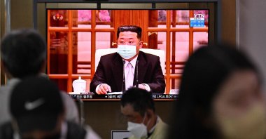 People sit near a screen showing a news broadcast of North Korea leader Kim Jong Un appearing in a face mask on television for the first time to order nationwide lockdowns after the North confirmed its first-ever COVID-19 cases, Seoul, S. Korea, May 12, 2022. (AFP Photo)