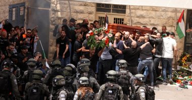 Family and friends carry the coffin of Al-Jazeera reporter Shireen Abu Akleh, who was killed during an Israeli raid in Jenin in the occupied West Bank, next to Israeli security forces, during her funeral in occupied East Jerusalem, Palestine, May 13, 2022. (Reuters Photo)
