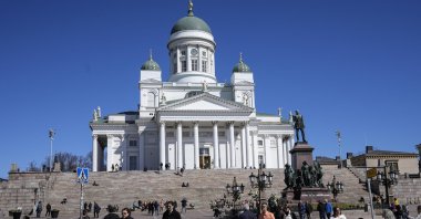 People walk at the Helsinki Cathedral under a blue sky in the city center of Helsinki, Finland, May 13, 2022. (AP Photo)