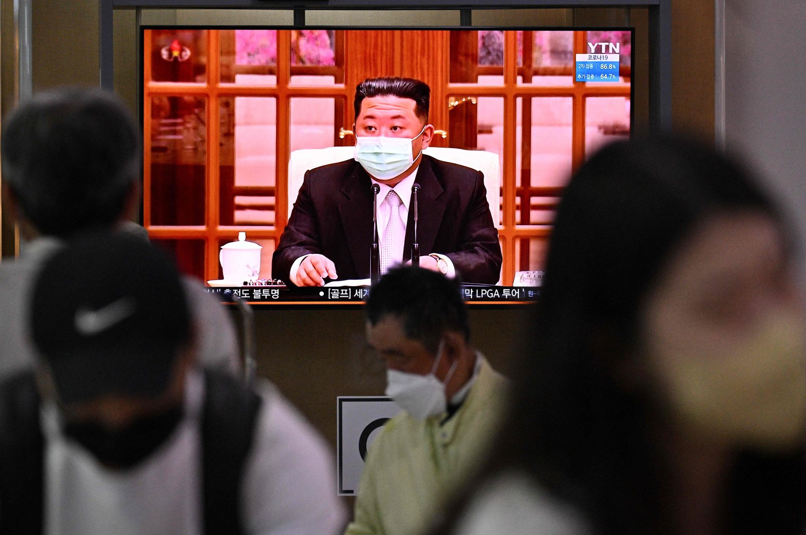 People sit near a screen showing a news broadcast of North Korea leader Kim Jong Un appearing in a face mask on television for the first time to order nationwide lockdowns after the North confirmed its first-ever COVID-19 cases, Seoul, S. Korea, May 12, 2022. (AFP Photo)