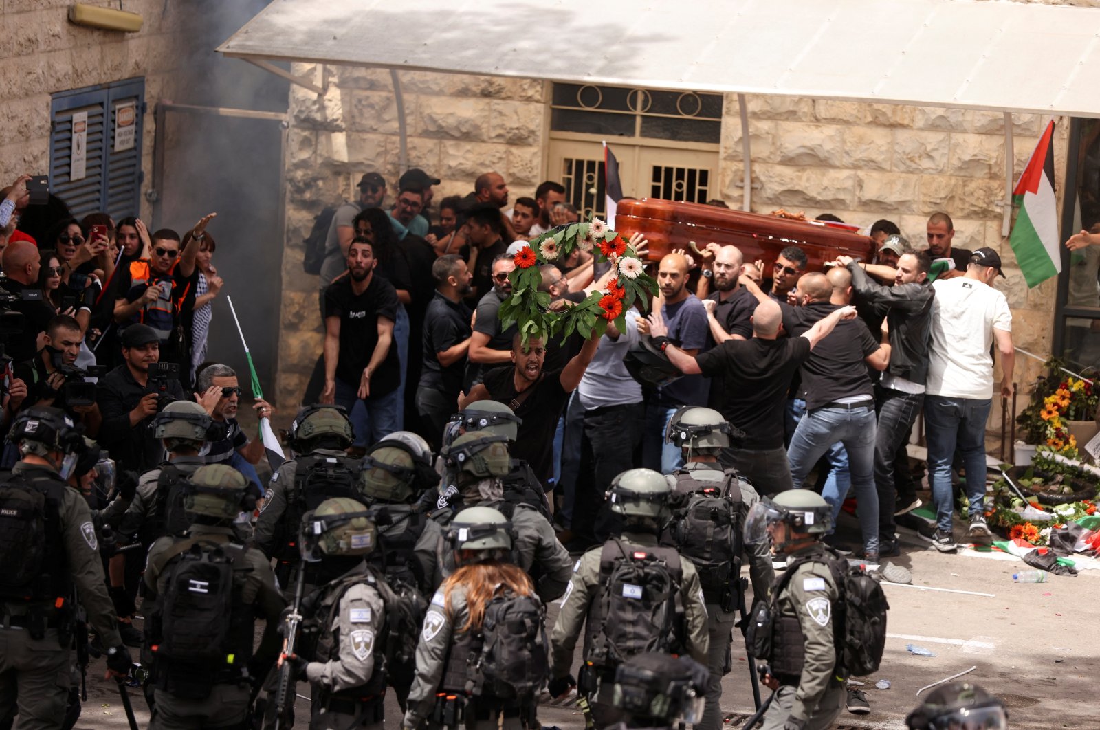 Family and friends carry the coffin of Al-Jazeera reporter Shireen Abu Akleh, who was killed during an Israeli raid in Jenin in the occupied West Bank, next to Israeli security forces, during her funeral in occupied East Jerusalem, Palestine, May 13, 2022. (Reuters Photo)