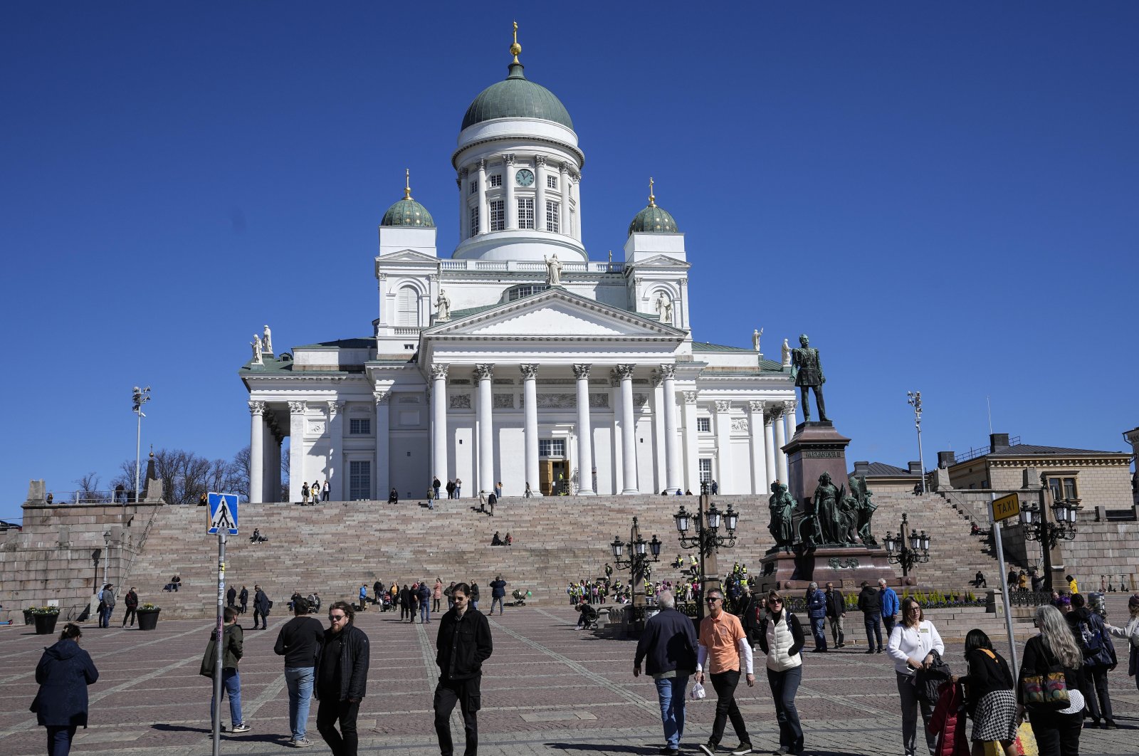 People walk at the Helsinki Cathedral under a blue sky in the city center of Helsinki, Finland, May 13, 2022. (AP Photo)